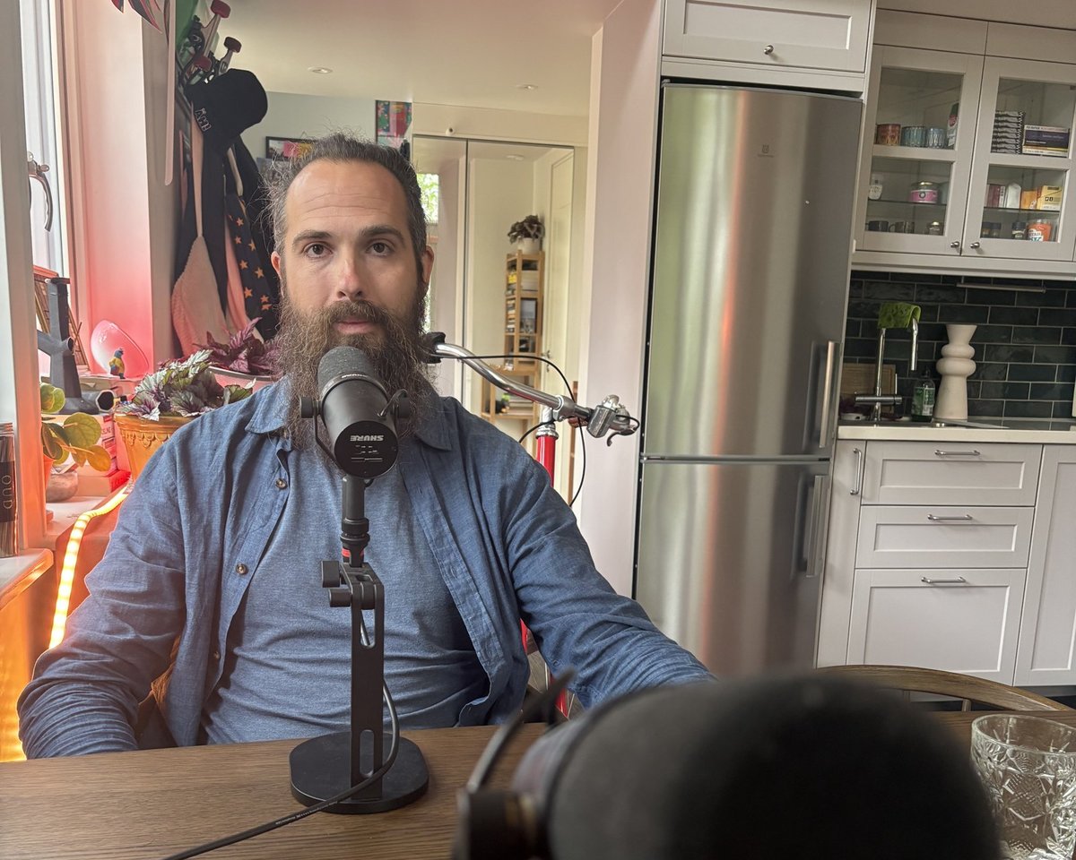 Navid Modiri vid mikrofonen i sin poddstudio hemma, 2026.